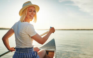 smiling-young-woman-canoeing-on-a-lake-in-summer