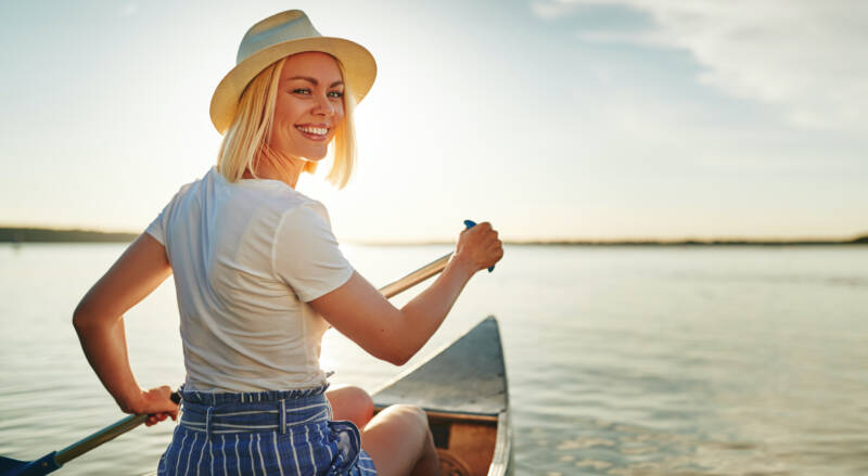 smiling-young-woman-canoeing-on-a-lake-in-summer